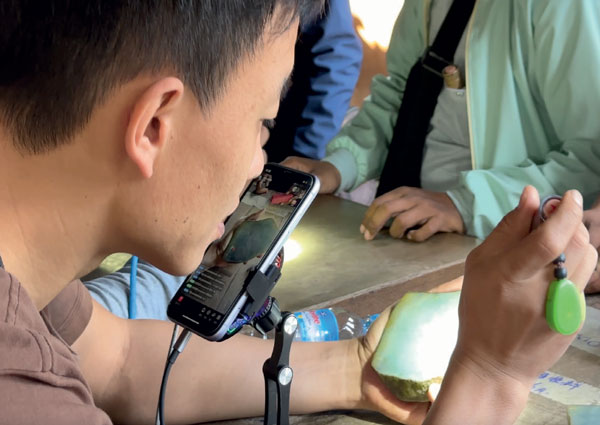 A live-streamer showing rough Fei Cui to a Chinese buyern by phone. (Photo: Andrew Lucas. ©Guild Gemology Education)